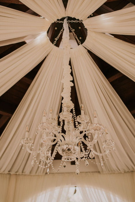 Chandelier in the middle of starburst draping. Draping and lighting by Draping by Kim