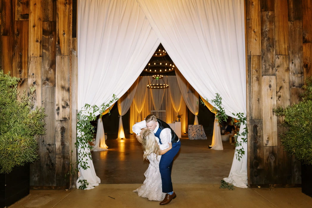 Inside barn at Greengate Barn in Edna Valley drapped with half cabanas at the posts, a cabana backdrop and barn door draping. Draping by: Draping by Kim and photography by Loveridge Photography