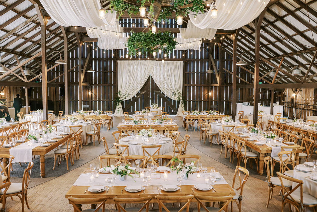 Sheer ivory draping in a cabana style on the barn doors and pillow draping on the ceiling at Santa Margarita Barn. Draping by: Draping by Kim